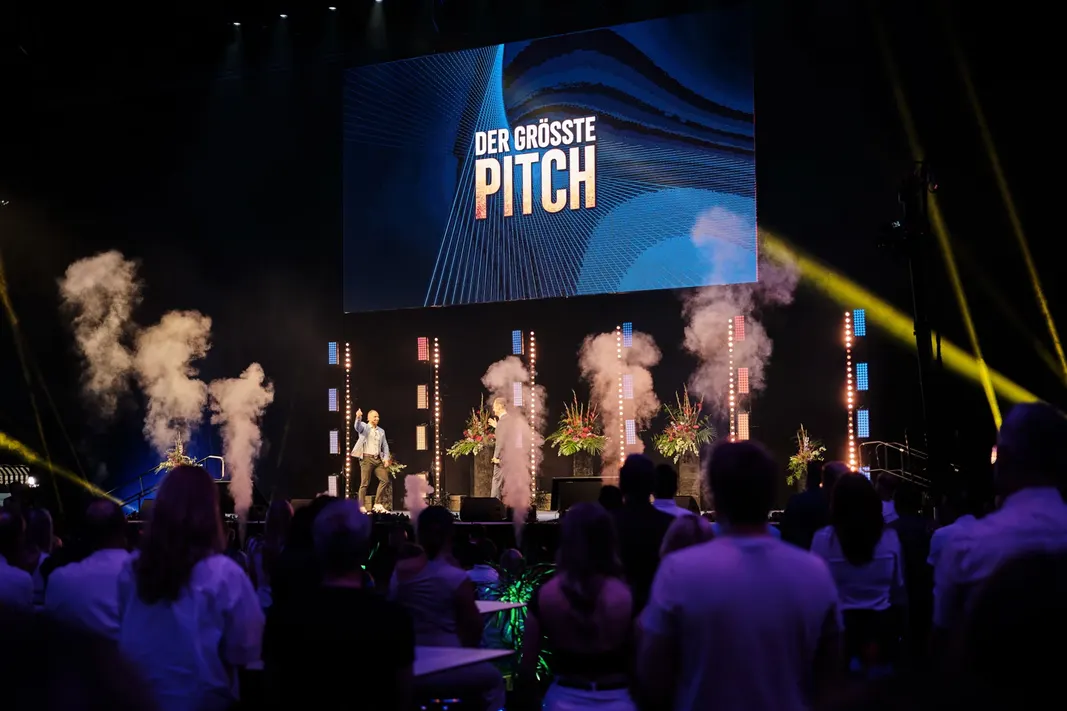 Der Schriftzug „Der größte Pitch“ auf der Videowand, davor Nebelsäulen.